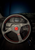 Black 14-inch racing steering wheel with red stitching and 3-spoke design by Jack Spania Racing, ideal for sports car interiors